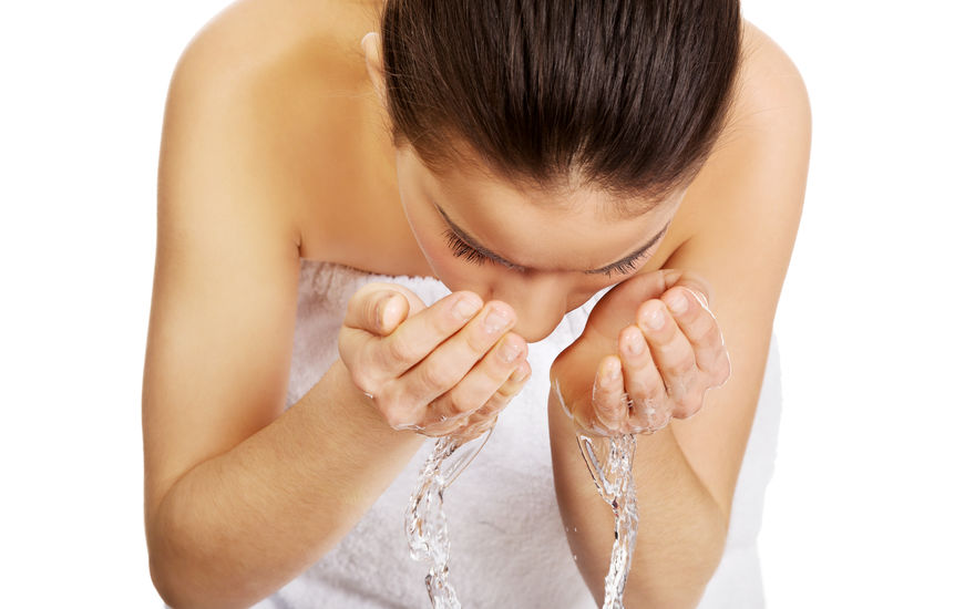 Woman washing her clean face with water.